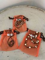 Group shot of three Chan Luu necklaces in orange mesh pouches