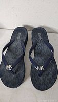 Top view of both sandals showing straps, MK logo hardware, monogram footbed