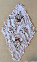 Full view of diamond-shaped runner with candle and poinsettia embroidery