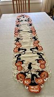 Full view of white runner on table showing pumpkin and cat motif