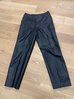 Full view of black leather pants laid flat