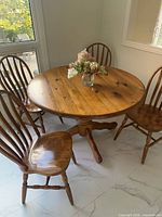Round solid pine table with four matching chairs placed around it