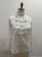 Front view of sheer ivory blouse on dress form showing jabot and sleeve cuffs