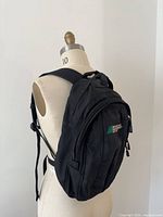 Full view of MEC black daypack on dress form showing size and strap configuration
