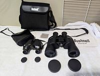 Both binoculars, their cases, caps, strap, cloth and booklet laid out