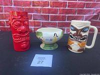 Three ceramic tiki-themed drinkware pieces on table