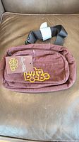 Front view of burgundy corduroy fanny pack showing TimBiebs tag and attached retail tag