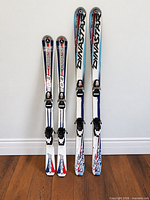 Both pairs of skis standing side by side showing complete items and bindings
