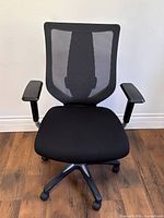 Front view showing mesh back, padded seat, armrests, five-star caster base