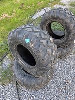 Four ATV tires stacked showing tread pattern and overall condition