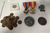 Overview showing medals, badge, challenge coins, holdered coin and pile of Lincoln cents
