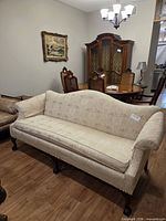 Full view of camelback sofa facing camera showing upholstery and legs