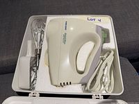 Mixer body in storage case with power cord and one whisk visible