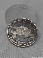 Obverse of coin in capsule showing station design and inscriptions