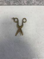 Front view of brass scissors pendant showing loop and patina