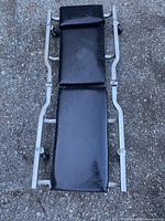 Top view of creeper showing black padded sections and metal frame with casters