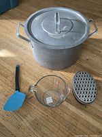 Top view of stockpot with lid on, spatula, measuring cup, grater