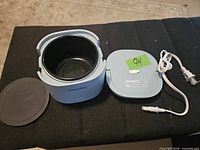 Cooker open showing inner pot, detached lid, power cord, silicone pad