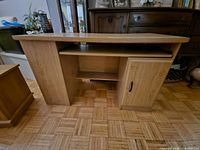 Front view of light oak laminate computer desk showing keyboard tray and cabinet