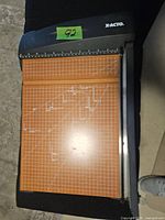 Top view of X-ACTO orange base guillotine paper cutter showing grid and cutting arm