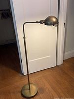 Full view of antique brass floor lamp showing height, stem, round base, adjustable head