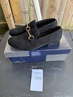 Side view of black loafers on original Amali box