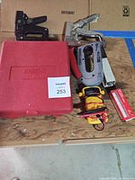 Overall lot on bench showing both staplers, multimeter, case, staples
