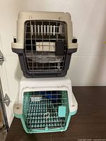 Two stacked plastic pet carriers showing colors and wire doors