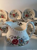 Creamer in foreground with cups and plates behind