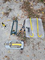 All items laid out on ground: sprinklers, pry bars, hose parts, bin