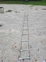 Full length view of metal chain ladder laid out on ground