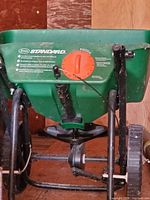 Actual spreader showing hopper, handle, wheels, rust