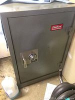 Front view of grey steel safe featuring mechanical combination dial, lever handle, and Edelbrock sticker