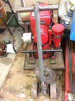 Top front view of red International Harvester LB engine mounted on metal base with handle and wheels