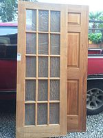 Two doors leaning against truck; French door with glass panes on left, solid pine 6 panel door on right.