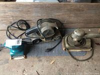 Top view showing all three sanders: Mikita palm sander, Craftsman belt sander, and Black & Decker vintage sander, all with cords.