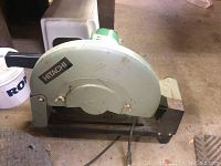 Side view of Hitachi chop saw showing brand name and general build with metal casing and black handle.