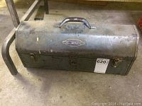 Full view of the vintage metal Craftsman toolbox showing overall shape, handle, and latches. The toolbox exhibits signs of wear and surface rust.