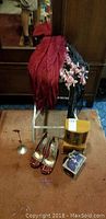 Photo of the lot showing scarves draped over a white metal stool, a wooden musical jewellery box with glass panels, a wooden jewellery box with ornate detailing, a metal necklace tree stand, and a pair of red and black houndstooth high heeled shoes with buckles.