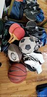 Photo showing various sporting goods including skateboard, cleats, soccer ball, football, basketball, winter hats, and ice skates.