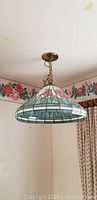 Photo of Tiffany style stained glass hanging lamp showing floral and geometric design from side angle.