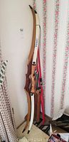 Three recurve bows leaning against wall (white Victory and two wood-tone)