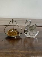 Condiment stand with amber glass dish, spoon, and plastic swan dish side by side