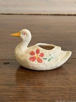 Left side view of ceramic goose holder showing floral paint and opening