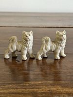 Front view of both white Akita dog figurines