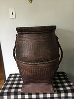 Front view of woven rattan rice bin on wood base