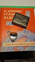 Stamp album front cover and Flame Crest lighter in box