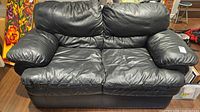 Front view of black leather loveseat showing overall design and condition