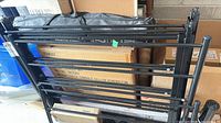 Stacked black metal frame sections leaning against boxes