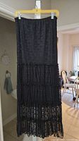Black tiered skirt hanging on hanger, full view